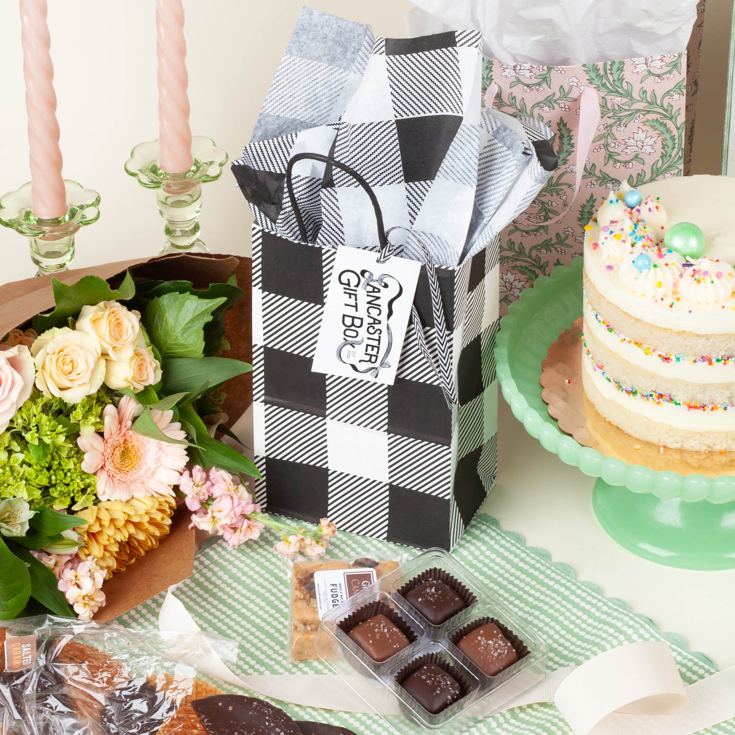 Nosh size wedding welcome bag in black and white gingham packaging on a light background, filled with Pennsylvania small-batch treats including Stroopies, and Groff's fudge.