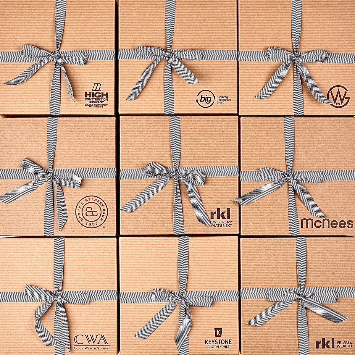 A 3x3 grid of kraft paper gift boxes tied with gray ribbon bows, each box printed with a different brand logo including High, Big, W, CWA, Keystone, and McNeles.