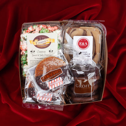 Holiday Nosh gift box on a red velvet background, filled with seasonal popcorn, chocolate pretzels, chocolate nut fudge, and peppermint stroopwafels from Lancaster, PA.