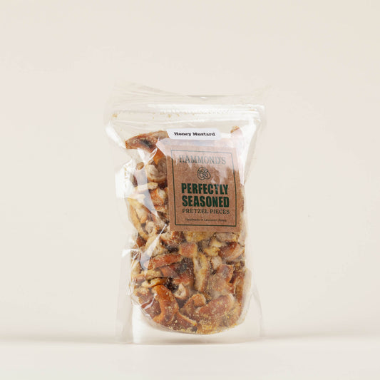 Eight-ounce bag of Hammond's Honey Mustard Pretzel Pieces on a light background, crunchy sourdough pretzel pieces with savory honey mustard seasoning, made in Lancaster, PA.