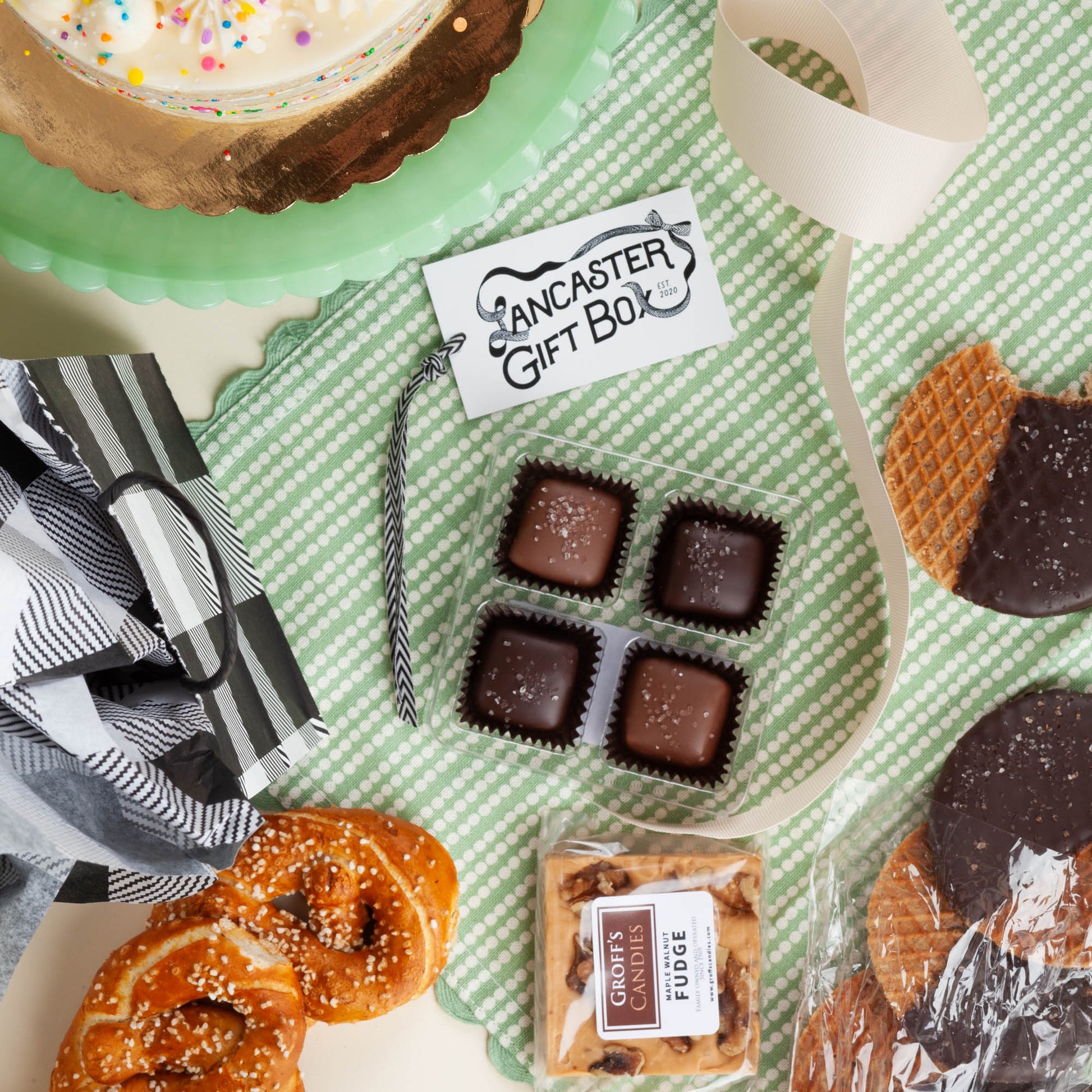Small size wedding welcome bag in black and white gingham packaging on a light green background, flatlay with Pennsylvania small-batch treats.